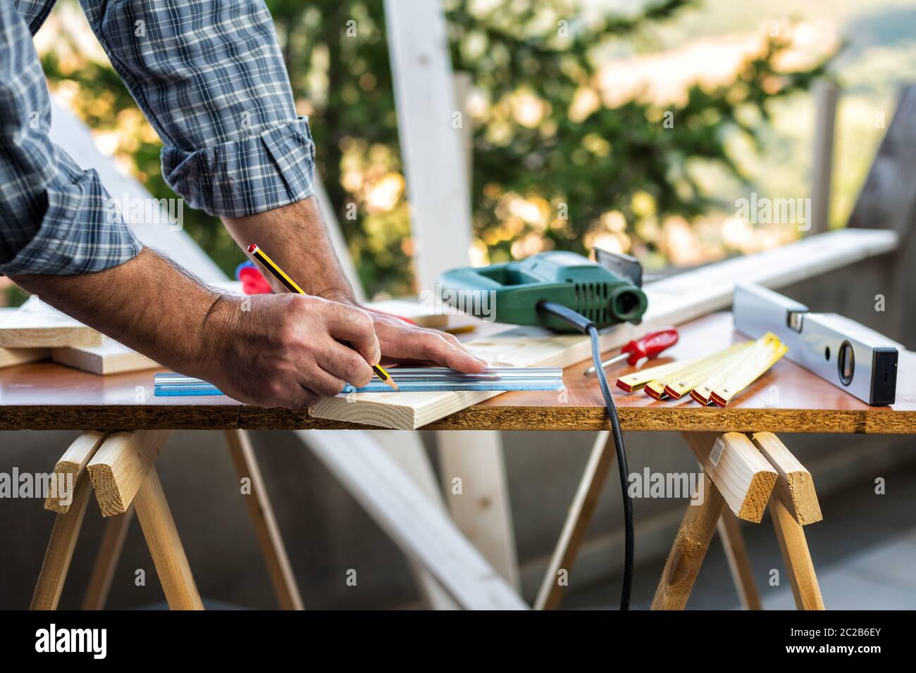 Adulto falegname artigiano con la matita e il righello tracciare la linea di taglio su un tavolo di legno. Lavori domestici fai da te. Fotografia stock. Foto Stock