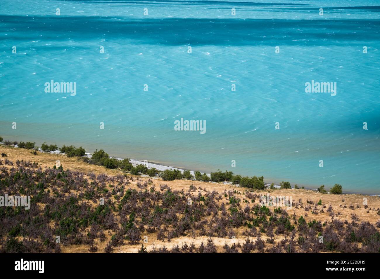 Acque blu glaciali del lago Pukaki, Nuova Zelanda, che incontrano la costa. Foto Stock