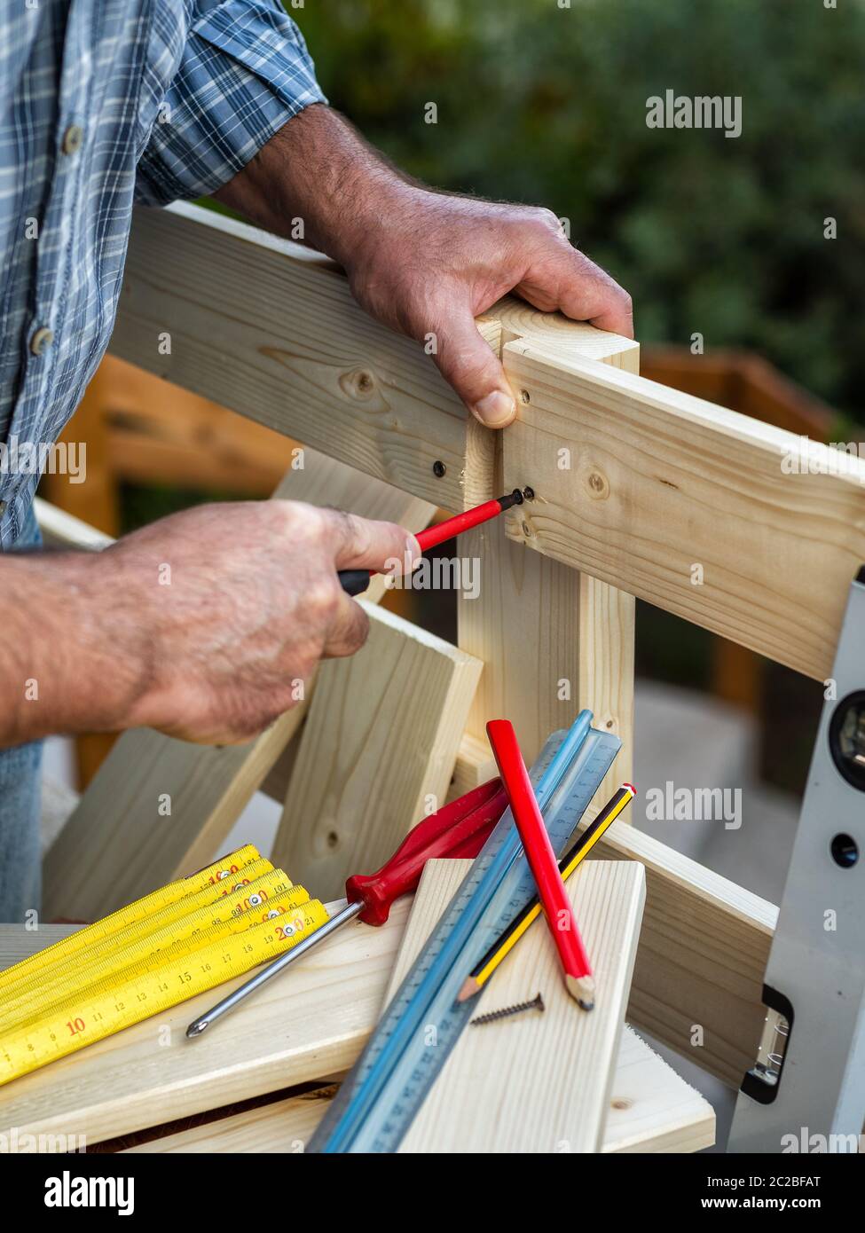 Adulto falegname artigiano con cacciavite avvitare la vite per fissare i pannelli di recinzione di legno. Lavori domestici fai da te. Fotografia stock. Foto Stock