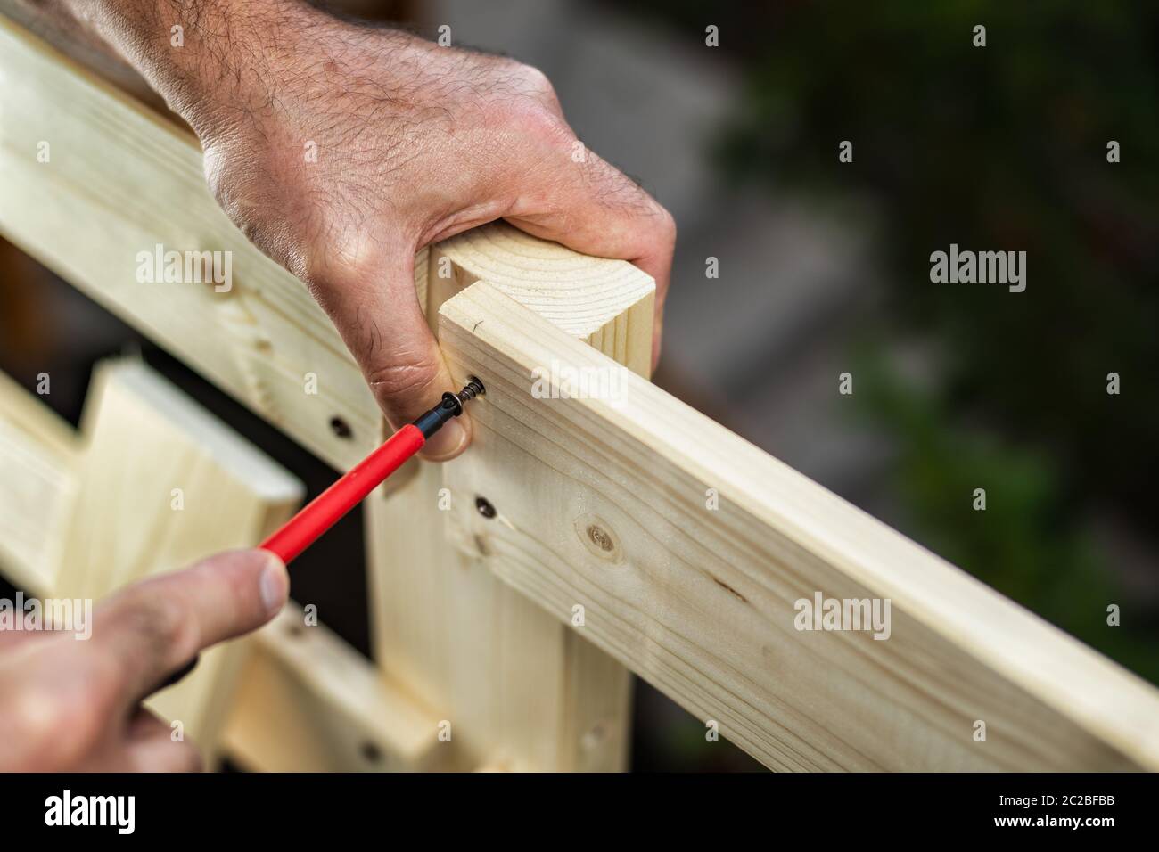 Adulto falegname artigiano con cacciavite avvitare la vite per fissare i pannelli di recinzione di legno. Lavori domestici fai da te. Fotografia stock. Foto Stock