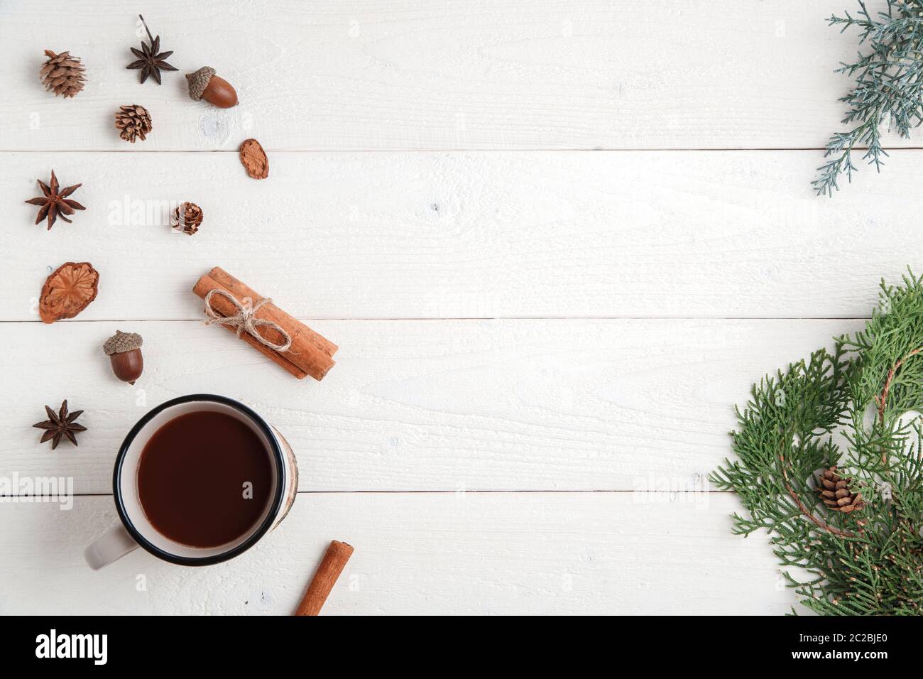 Nuovo anno di fondo. Cannella, stelle anice, rami di abete e una tazza di cioccolata calda su uno sfondo di legno bianco. Posa piatta superiore vi Foto Stock