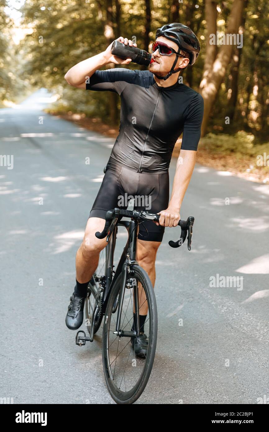 Ritratto di un uomo maturo in costume sportivo rinfrescante con acqua dopo  una lunga percorrenza in bicicletta. Uomo forte in casco e occhiali da vista  bere Foto stock - Alamy
