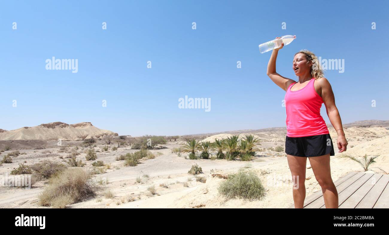 Donna si rinfresca con acqua dopo un allenamento nel deserto. Modello rilasciato Foto Stock