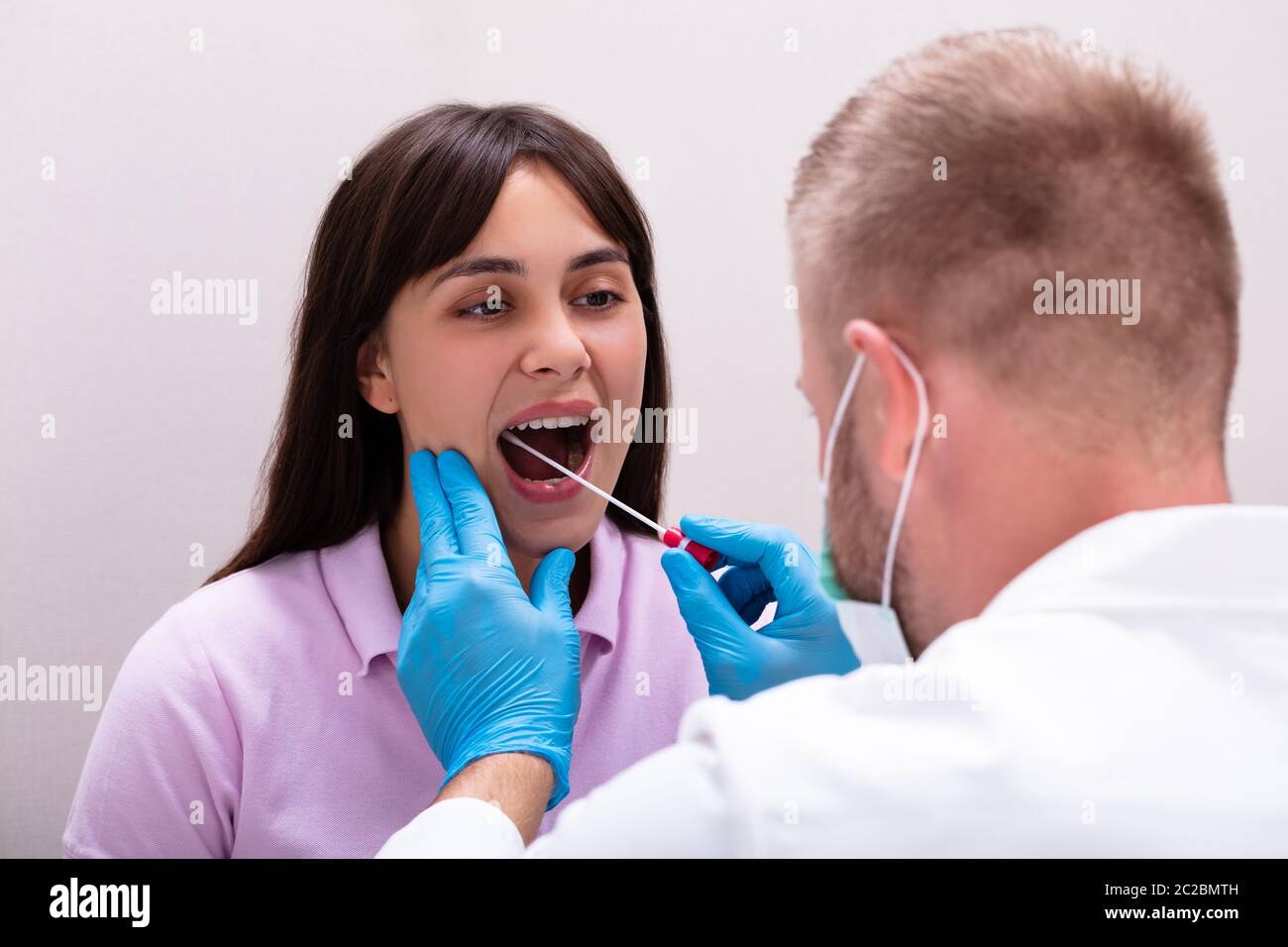 Vista posteriore di un medico di sesso maschile prendendo un fluido corporeo campione per il test del DNA Foto Stock