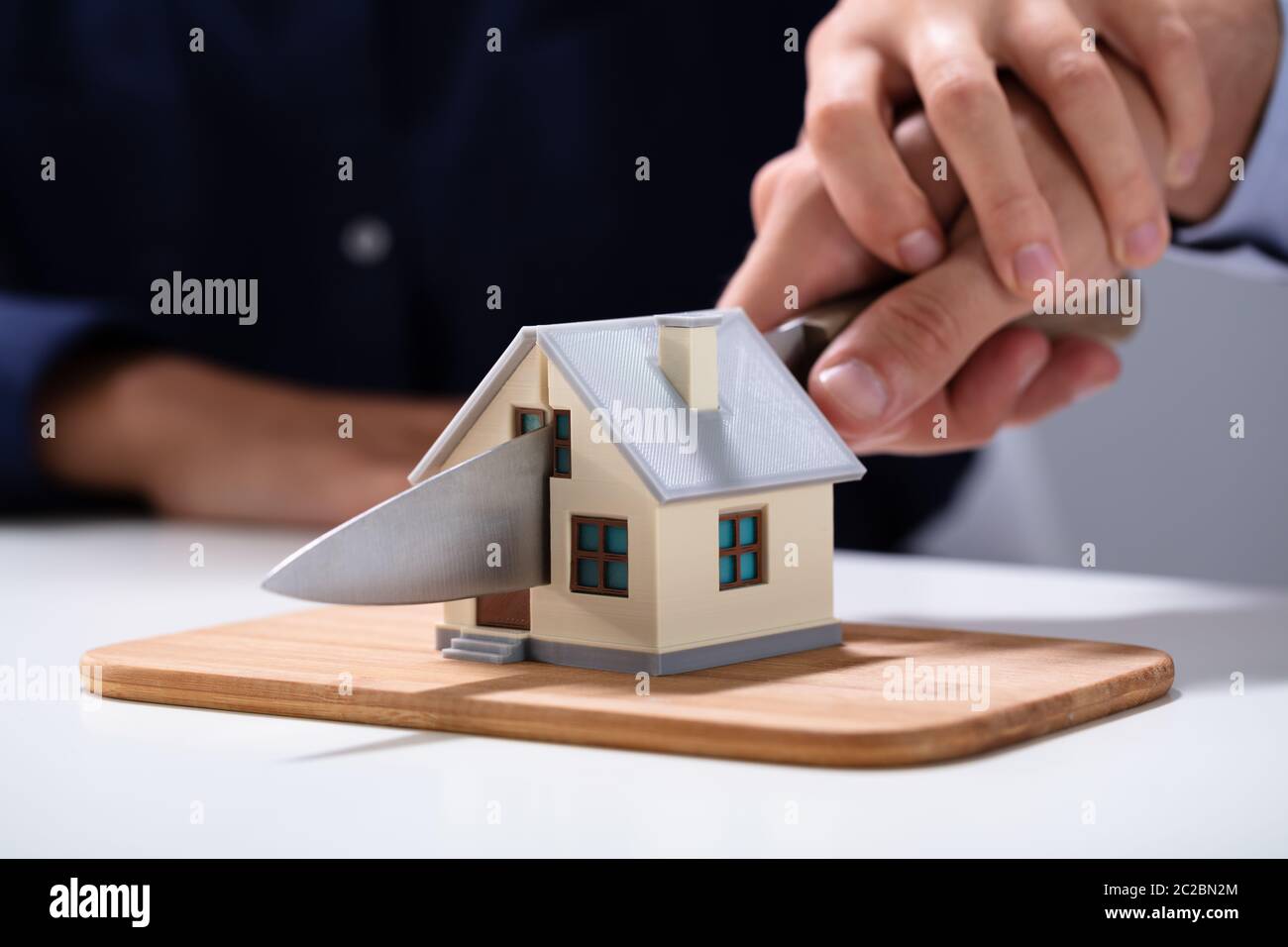 Coppia di taglio a mano la miniatura Modello di casa con il coltello sul tagliere Foto Stock