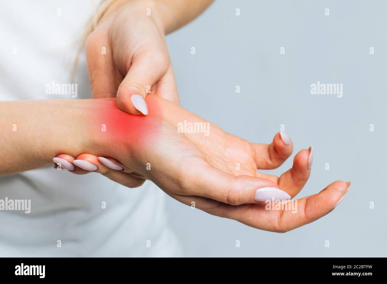 Closeup di braccia femminili che tengono il suo polso doloroso causato da un lavoro prolungato sul computer, laptop, colorato in rosso.Carpal tunnel sindrome, artrite, Foto Stock