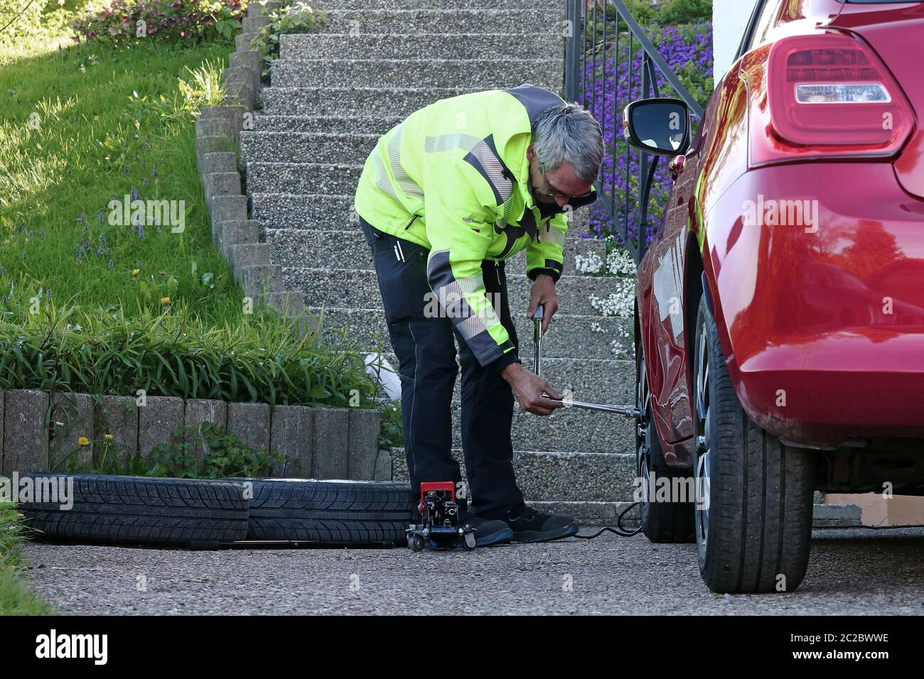 Un uomo cambia le gomme sulla sua auto. Sostituzione degli pneumatici estivi in primavera Foto Stock