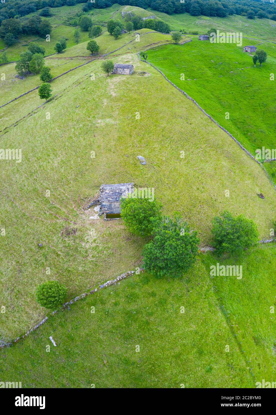 Vista aerea con un drone del paesaggio primaverile delle capanne e dei prati di pasiegas nella Valle di Miera nella Comunità Autonoma della Cantabria. Spagna, Europa Foto Stock