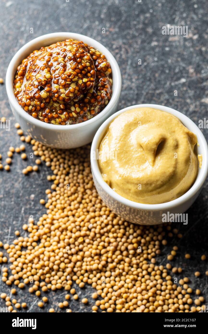 Giallo senape e grano intero e di senapa Semi di senape sul tavolo da cucina. Foto Stock