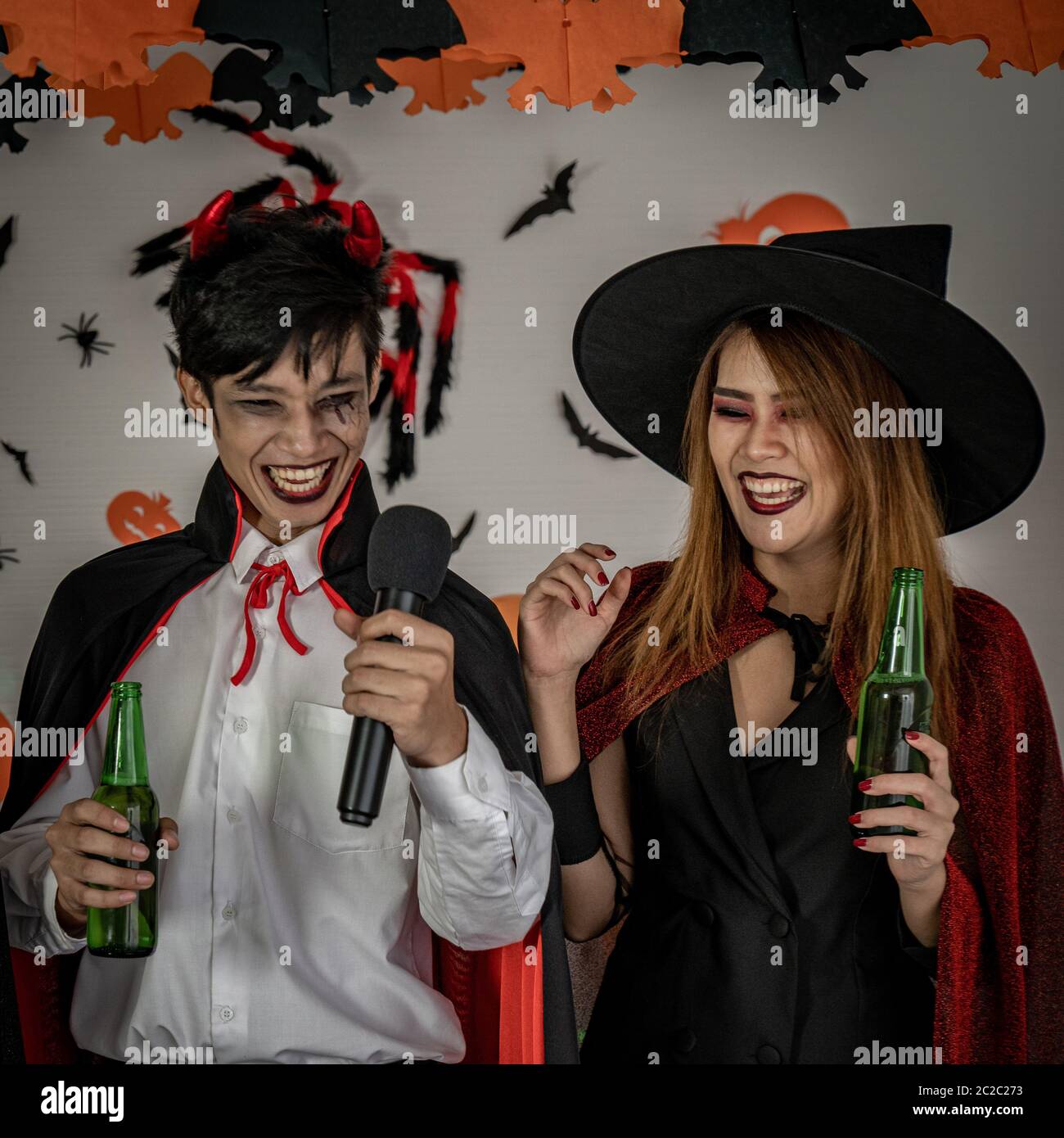 Un gruppo di giovani e di adulti di adolescente persone celebrare una festa di Halloween festa di carnevale in costume di Halloween di bere alcolici birra Foto Stock