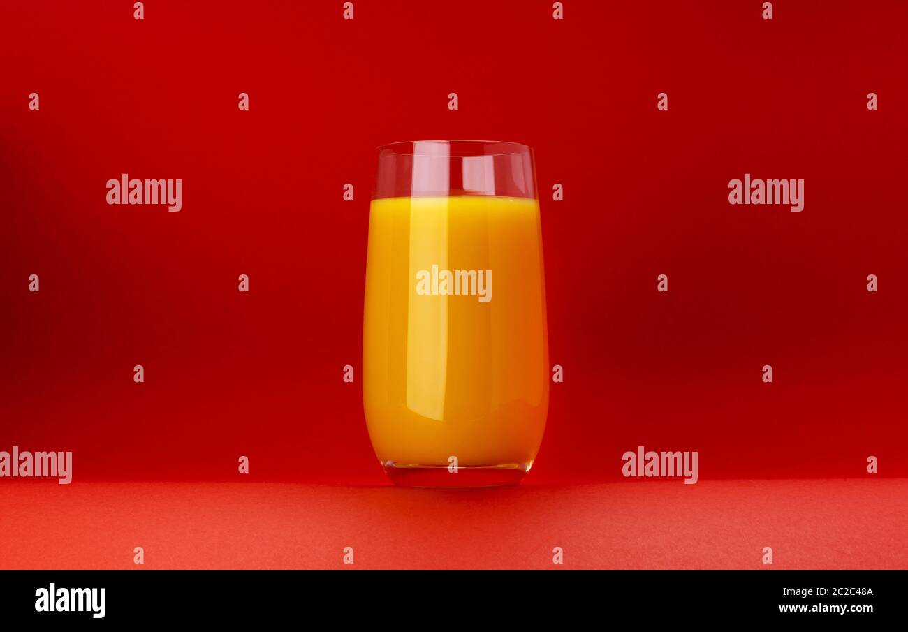 Bicchiere di succo d'arancia isolato su sfondo rosso con spazio per la copia Foto Stock