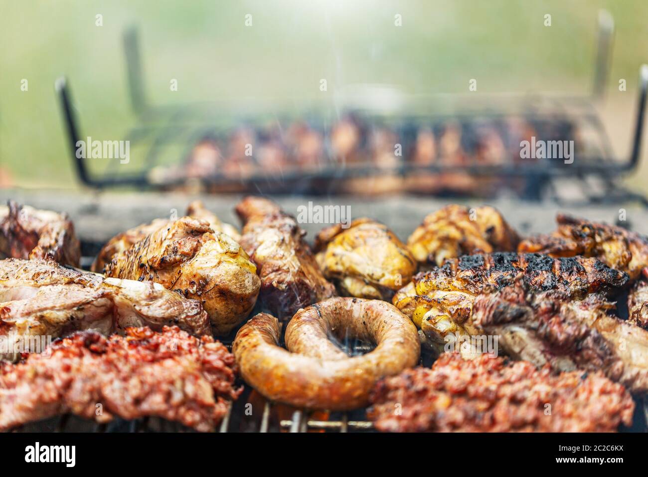 Barbecue salsicce fritte sfondo, primo piano. Kebab di salsiccia su carboni. Cucina tradizionale. Picnic in famiglia all'aperto. Messa a fuoco selettiva. Foto Stock