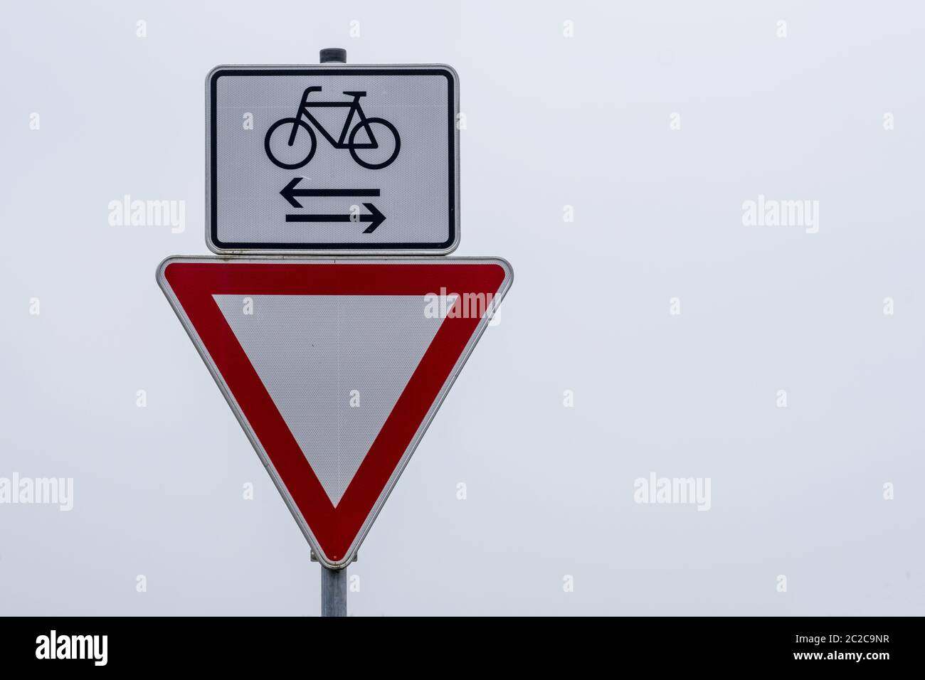 Prestare attenzione al segnale stradale a destra e ai ciclisti da sinistra e destra Foto Stock