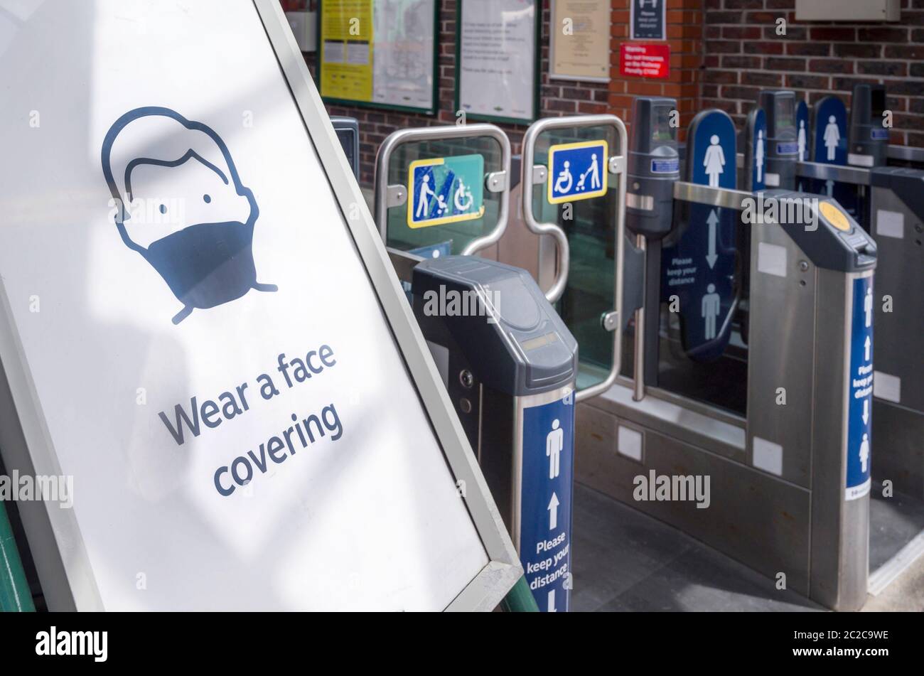 Poster all'ingresso di una stazione ferroviaria che chiede alle persone di indossare una copertura facciale a causa della pandemia del coronavirus nel giugno 2020, Inghilterra, Regno Unito. Foto Stock