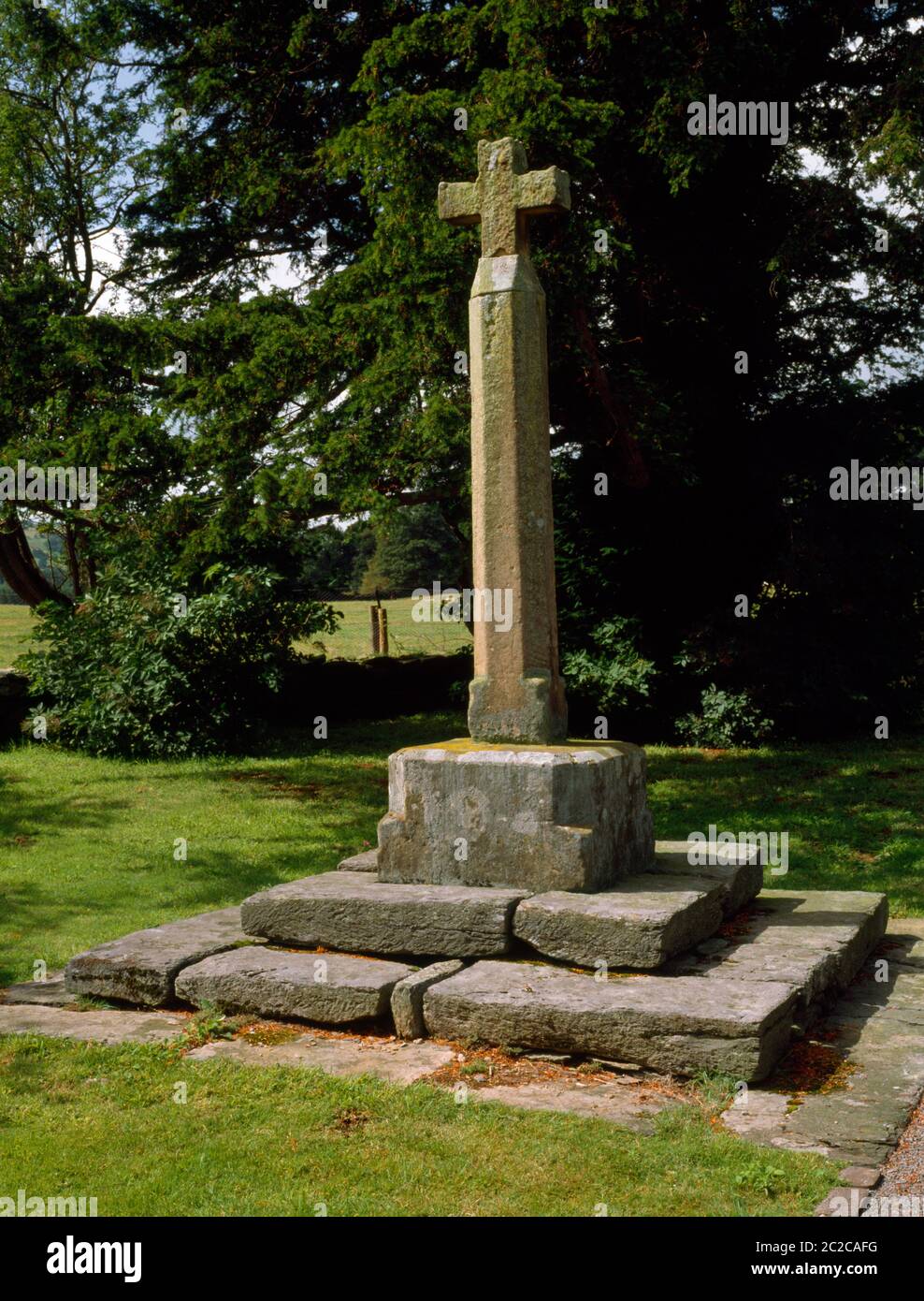 Vista W di una croce di pietra nei terreni della Rug Chapel, Denbighshire, Galles, Regno Unito: Costruito nel 1637 come cappella privata dal colonnello William Salisbury. Foto Stock