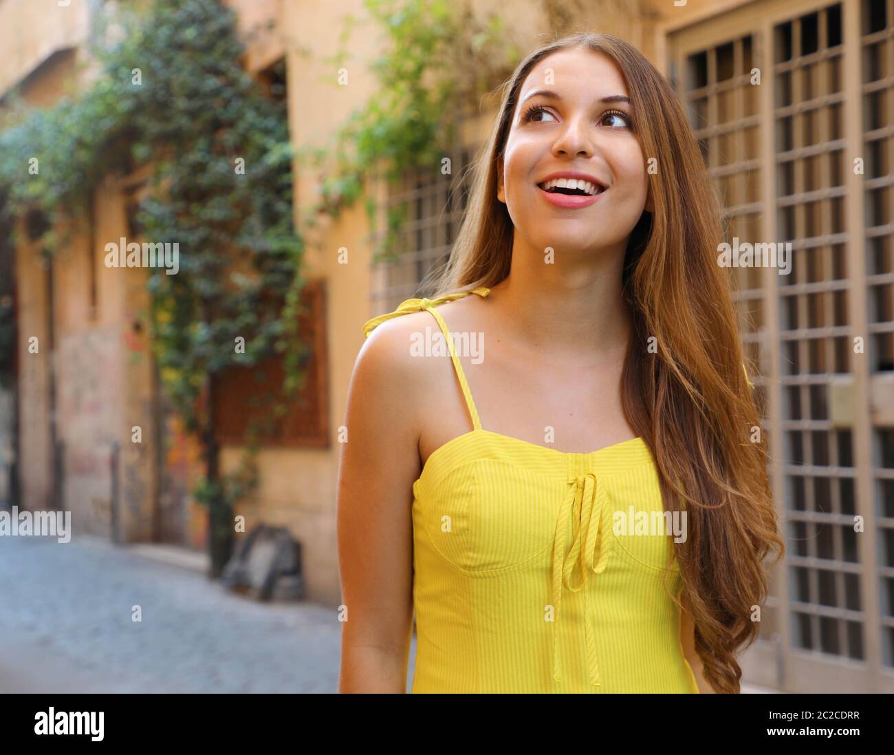 Ritratto di bella ragazza con i capelli lunghi in giallo abiti estivi camminando nel quartiere di Trastevere Roma, Italia. Foto Stock