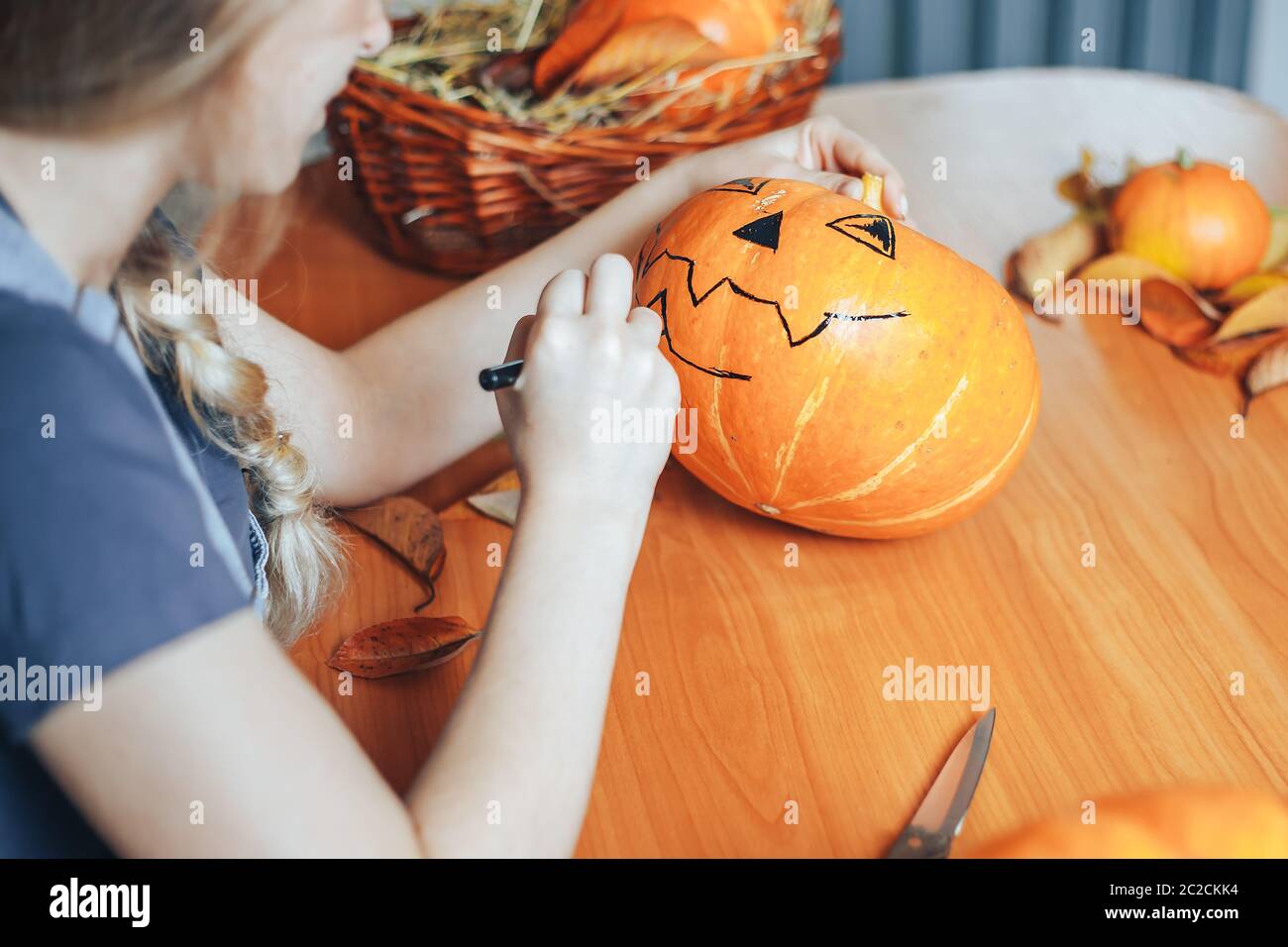 una bella donna bionda dipinge zucche per halloween a casa in cucina Foto Stock