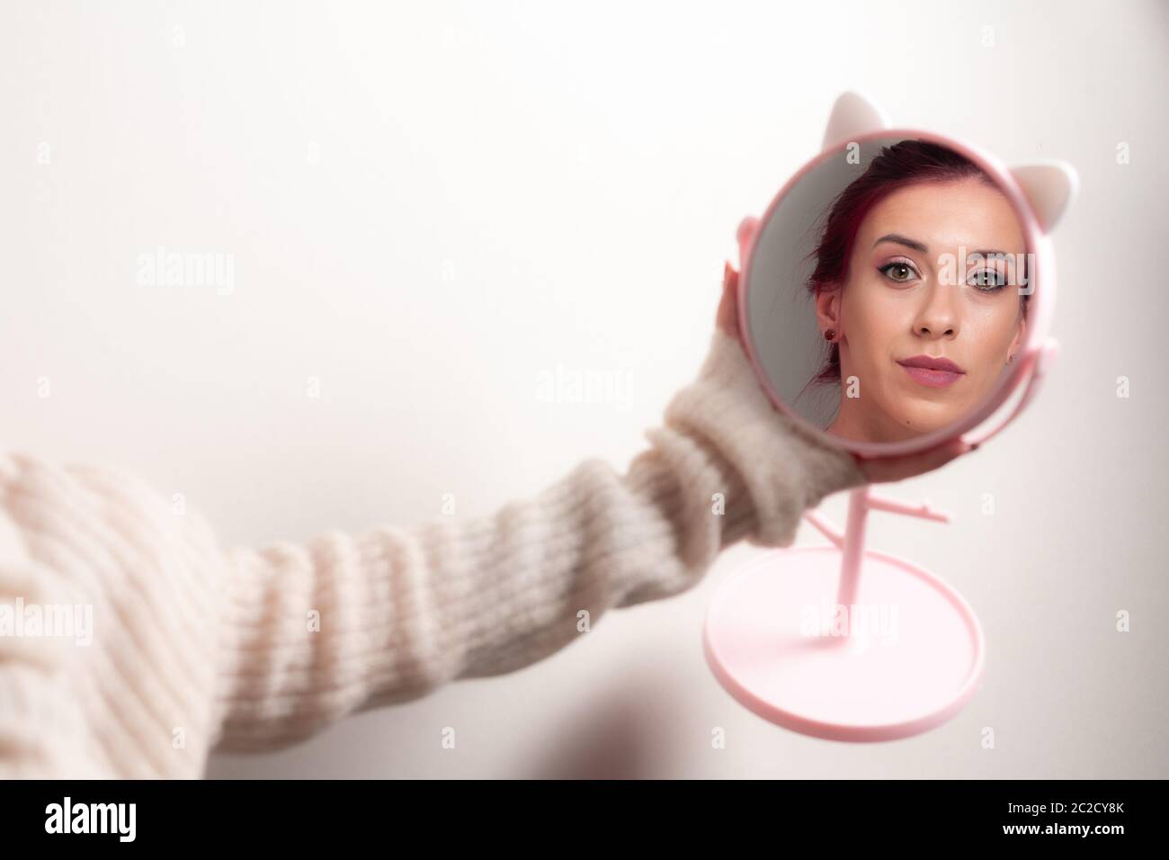 Una ragazza di trucco sta guardando in uno specchio rotondo. Foto Stock