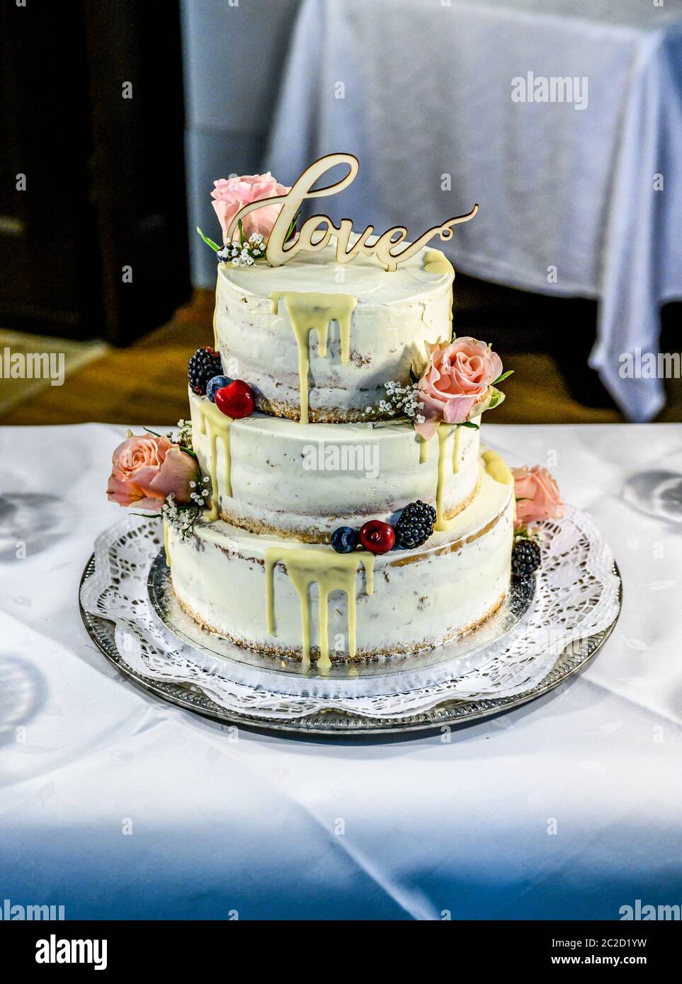 Bella torta nuziale con crema con amore di testo sulla parte superiore e fiori di colore rosa rose Foto Stock