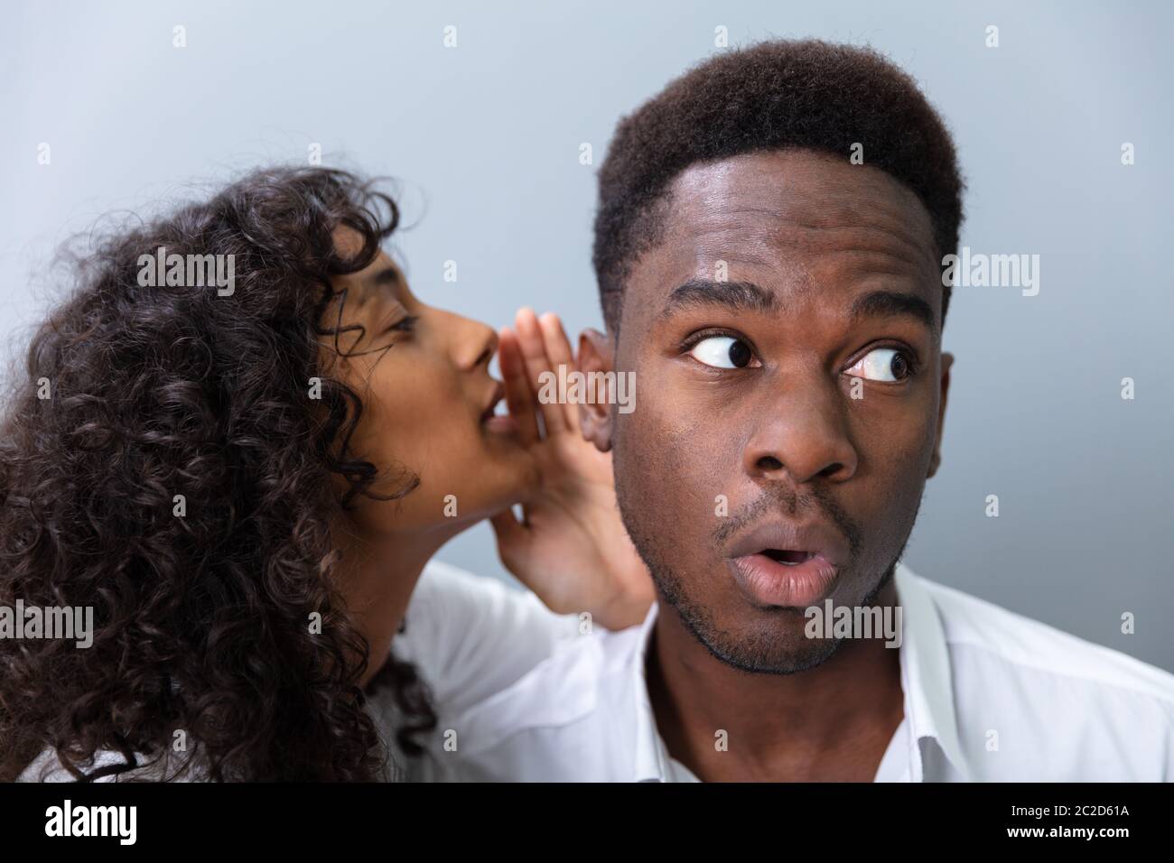 Imprenditore Whispering in orecchio dei colleghi in ufficio Foto Stock