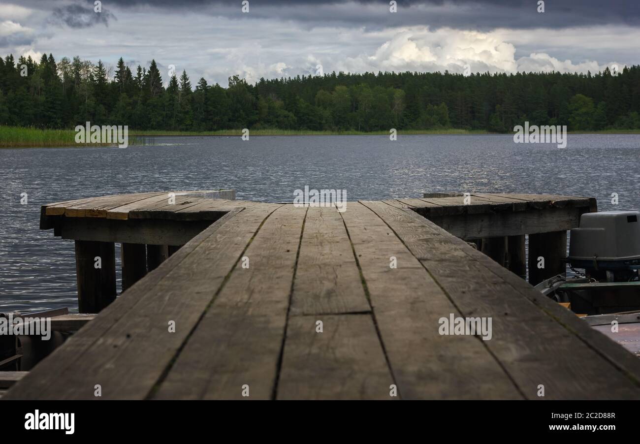 Vista pittoresca da un molo in legno su un lago forestale in tempo ventoso e nuvoloso. Paesaggio atmosferico con spazio per la copia, messa a fuoco selettiva. Lago Seliger Foto Stock