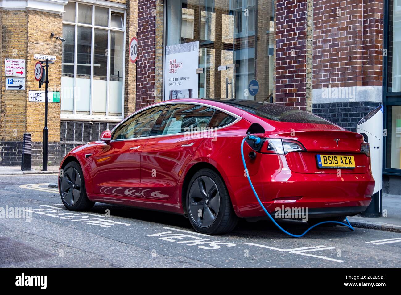 LONDRA, GIUGNO 2020: Una Tesla Model 3 rossa parcheggiata e in carica sulla strada della città Foto Stock