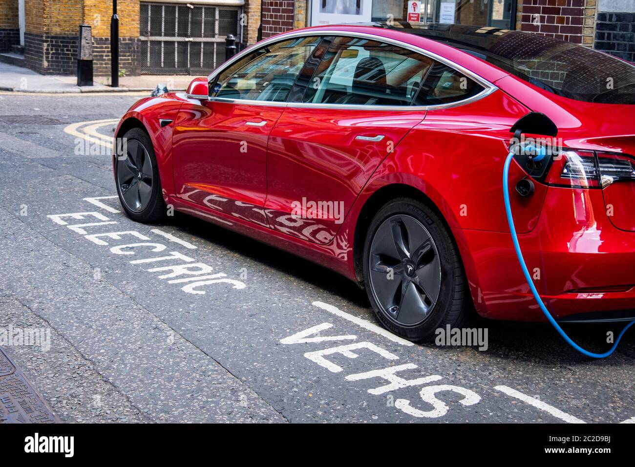 LONDRA, GIUGNO 2020: Una Tesla Model 3 rossa parcheggiata e in carica sulla strada della città Foto Stock
