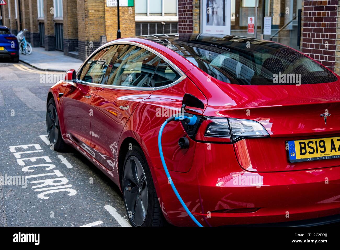 LONDRA, GIUGNO 2020: Una Tesla Model 3 rossa parcheggiata e in carica sulla strada della città Foto Stock