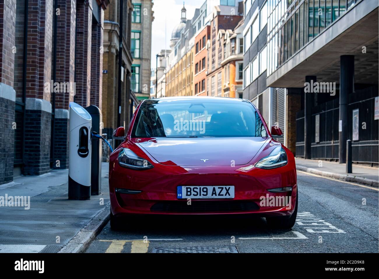 LONDRA, GIUGNO 2020: Una Tesla Model 3 rossa parcheggiata e in carica sulla strada della città Foto Stock