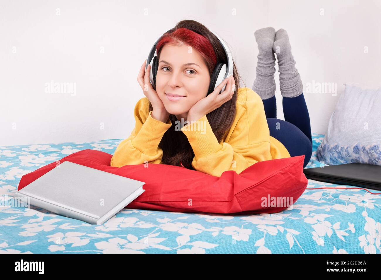 Musica break dopo una lunga giornata di studio. Giovane e bella ragazza distesa in letto, ascoltando musica dopo aver studiato. Foto Stock