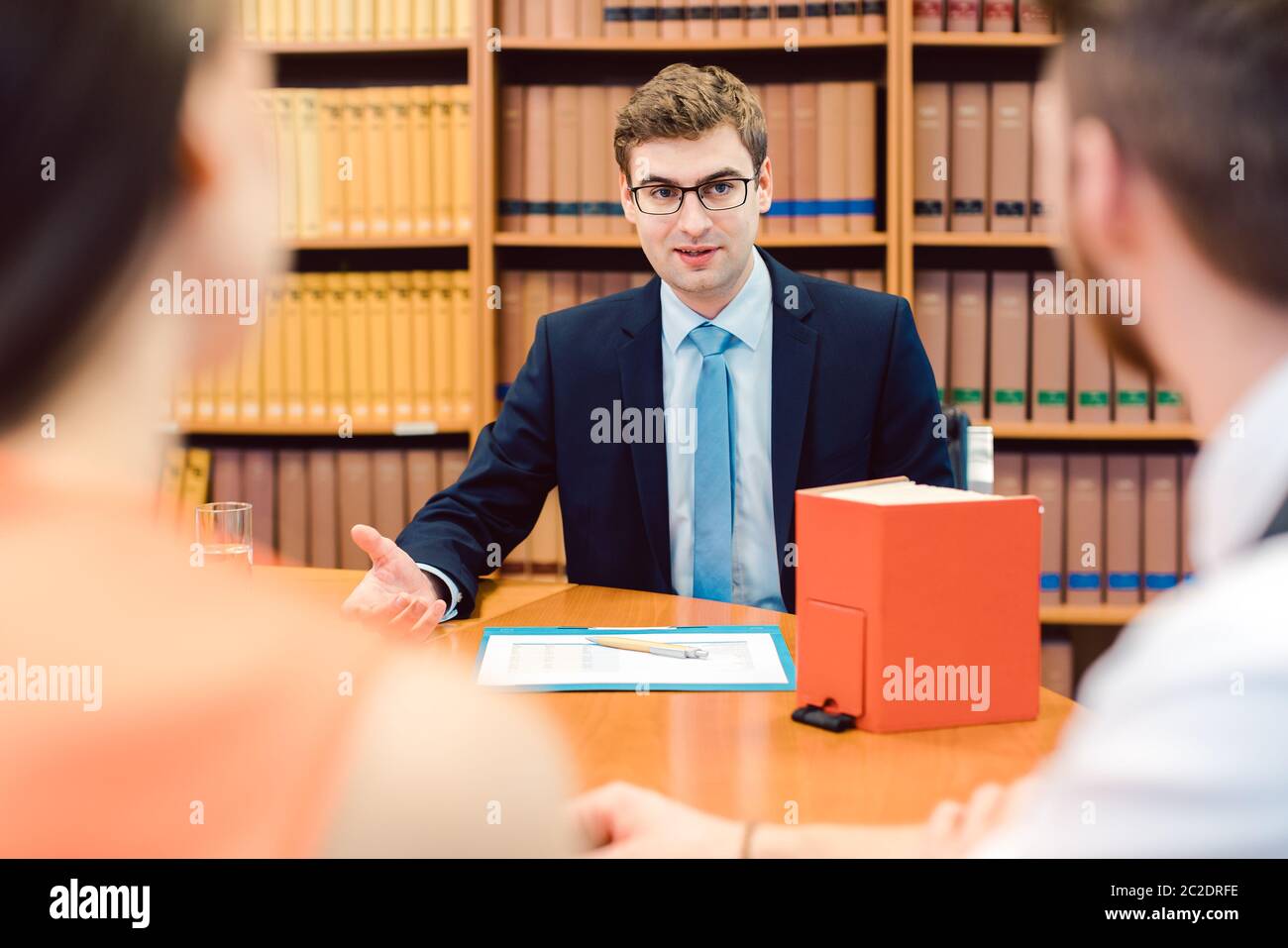 Notaio che consiglia la coppia sull'insediamento del matrimonio nel suo ufficio Foto Stock