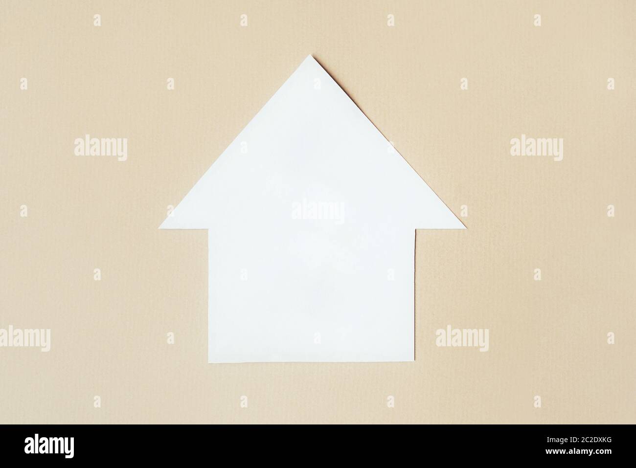 Modello cartaceo di una casa su sfondo beige. Foto Stock