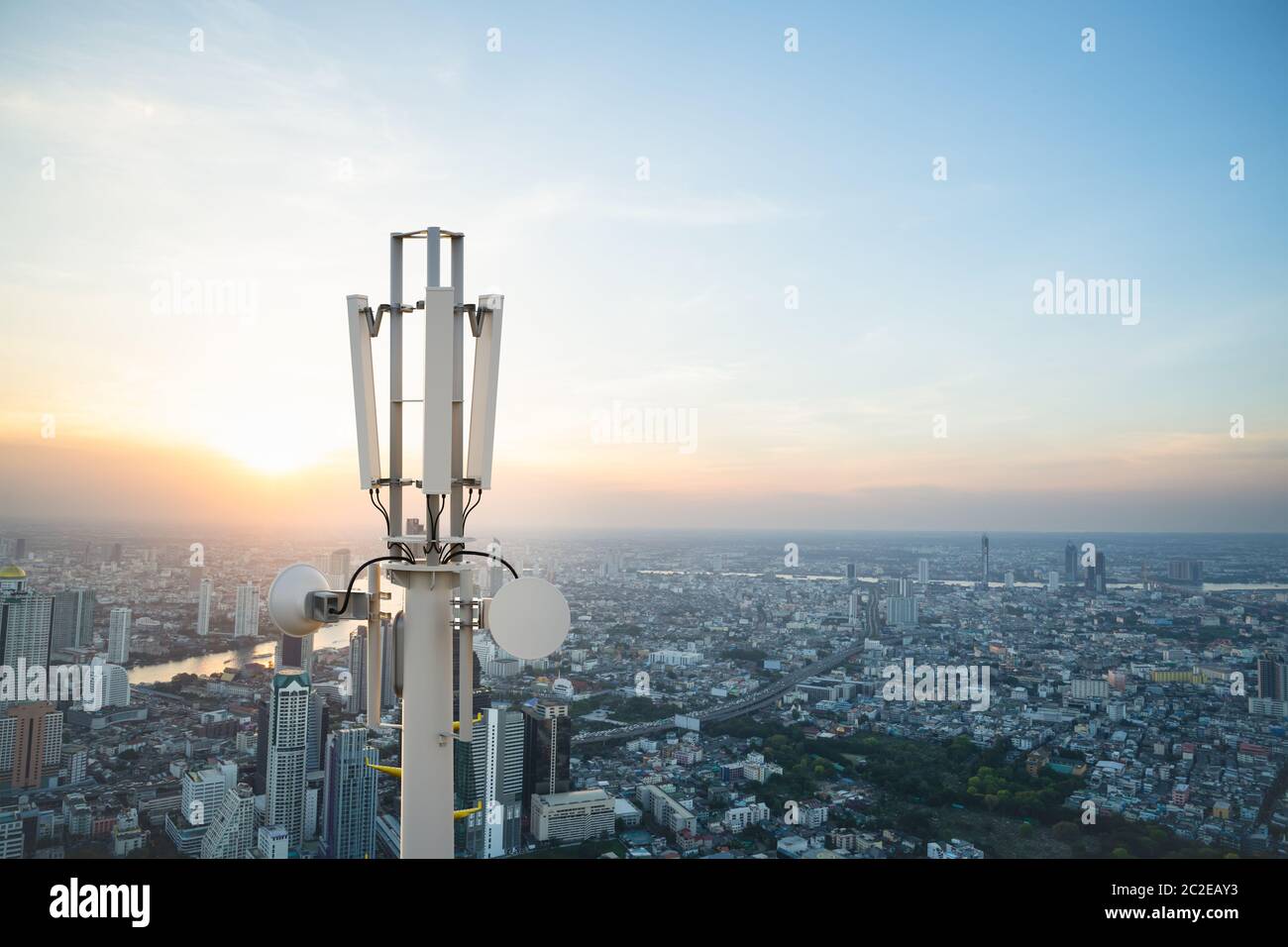 Torre di telecomunicazione con antenna di rete cellulare 5G su sfondo urbano Foto Stock
