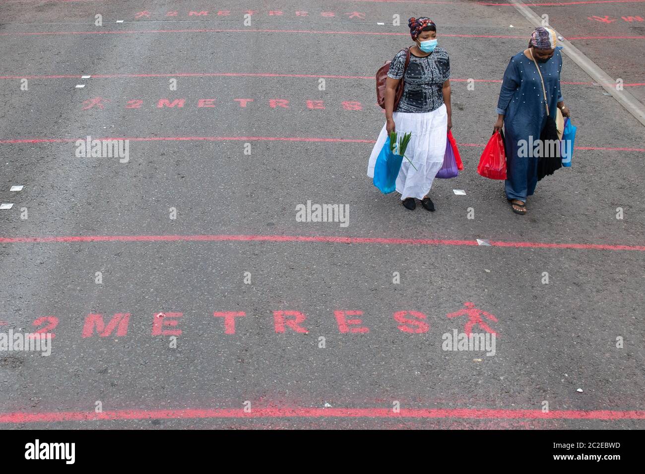 La gente cammina oltre due metri di marcature di distanza sociale al mercato di strada di Ridley Road nella parte est di Londra, come il governo considera rilassante linee guida ufficiali sulla distanza sociale a una distanza più breve di un metro. Il Segretario della Sanità Matt Hancock, sollecitato a ridurre la distanza sociale da due metri a un metro, ha detto ai Comuni: 'È il tipo di cosa che naturalmente vogliamo sollevare e dobbiamo fare in modo che sia attento e sicuro. Foto Stock