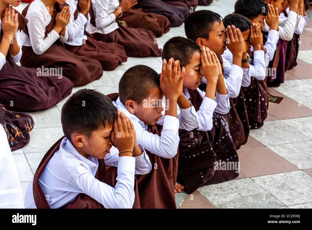 Un gruppo di bambini buddisti che pregano alla Pagoda Shwedagon, Yangon, Myanmar. Foto Stock