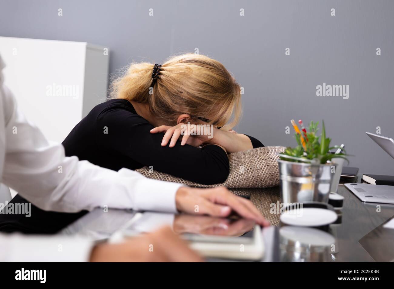 Bionda giovane imprenditrice dormendo mentre seduto al suo posto di lavoro Foto Stock