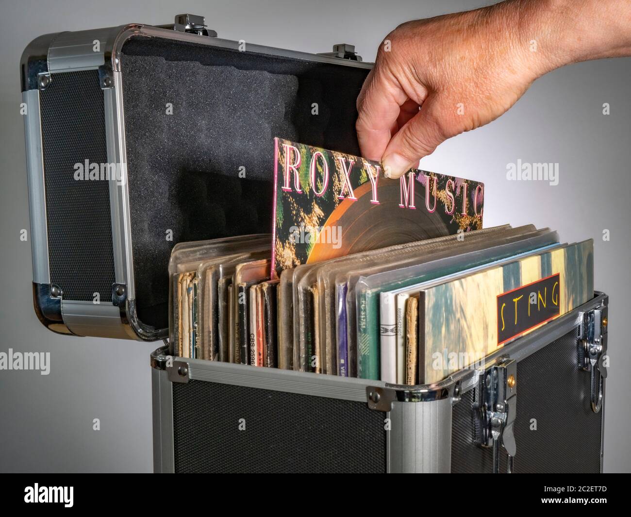 Man’s hand su un album in vinile/LP Roxy Music, in una custodia protettiva, che contiene dischi musicali in copertine di cartone, con un album Sting sul davanti. Foto Stock