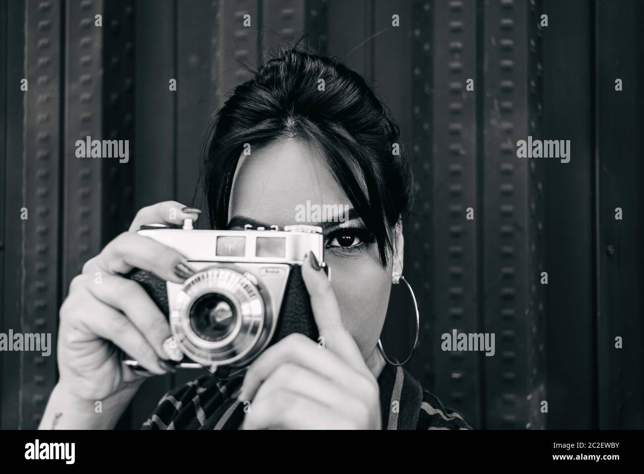 donna con una fotocamera antica che fa una foto guardando il suo obiettivo. Foto Stock