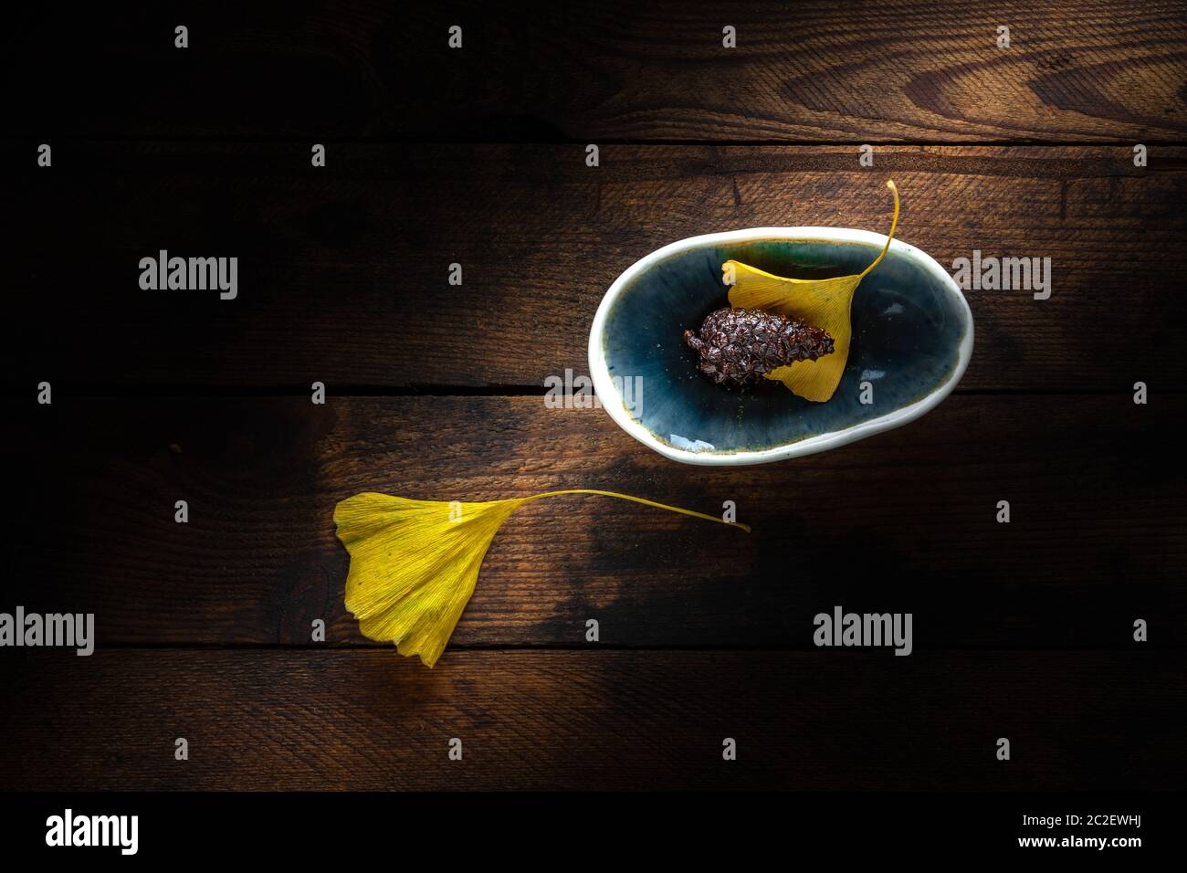 Cono di pino in una piccola ciotola su un vecchio sfondo di plnak di legno grugnoso Foto Stock