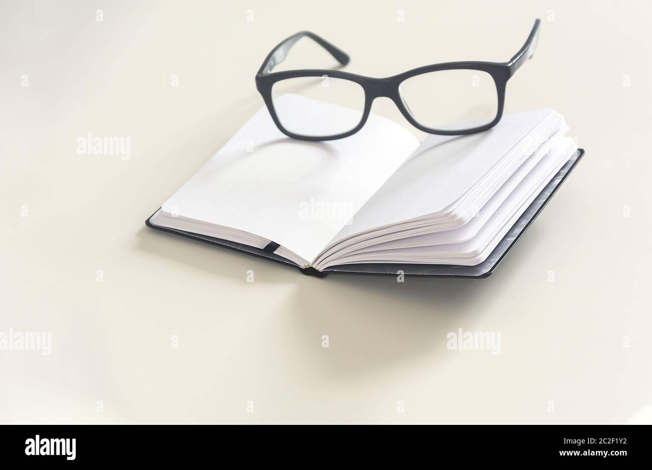 un paio di occhiali su un notebook aperto con pagine vuote. Foto Stock