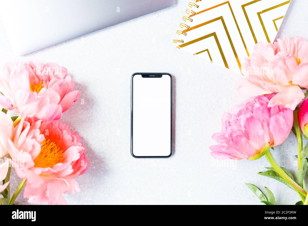 Ambiente di lavoro, visualizzazione desktop. Computer portatile, peony rosa e cellulare mock up. Spazio di lavoro donna. Spazio di copia. Foto Stock