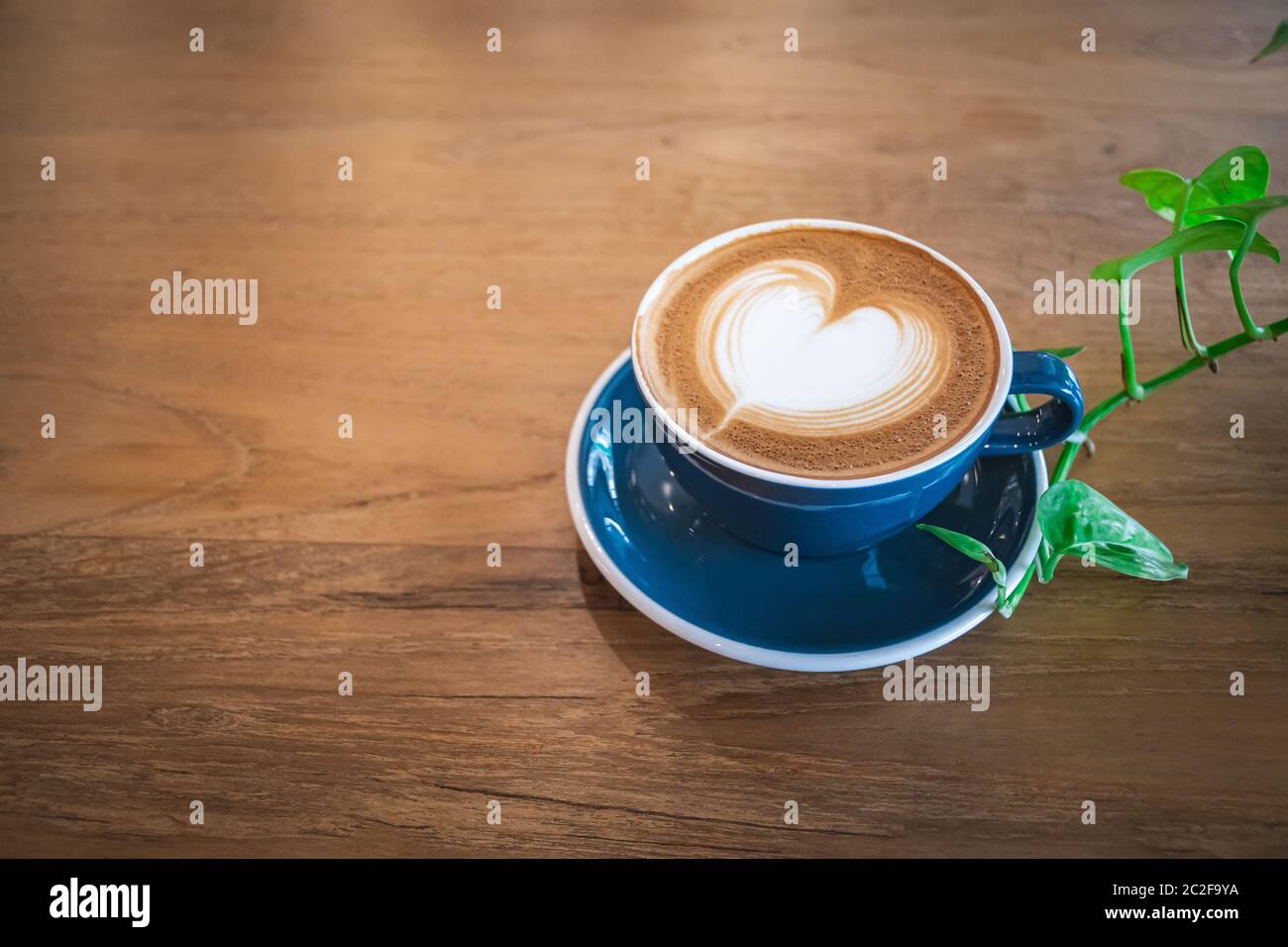 Bella una tazza blu di cappuccino caldo caffè con latte art su tavola di legno, fuoco selettivo per sfondo bevanda Foto Stock