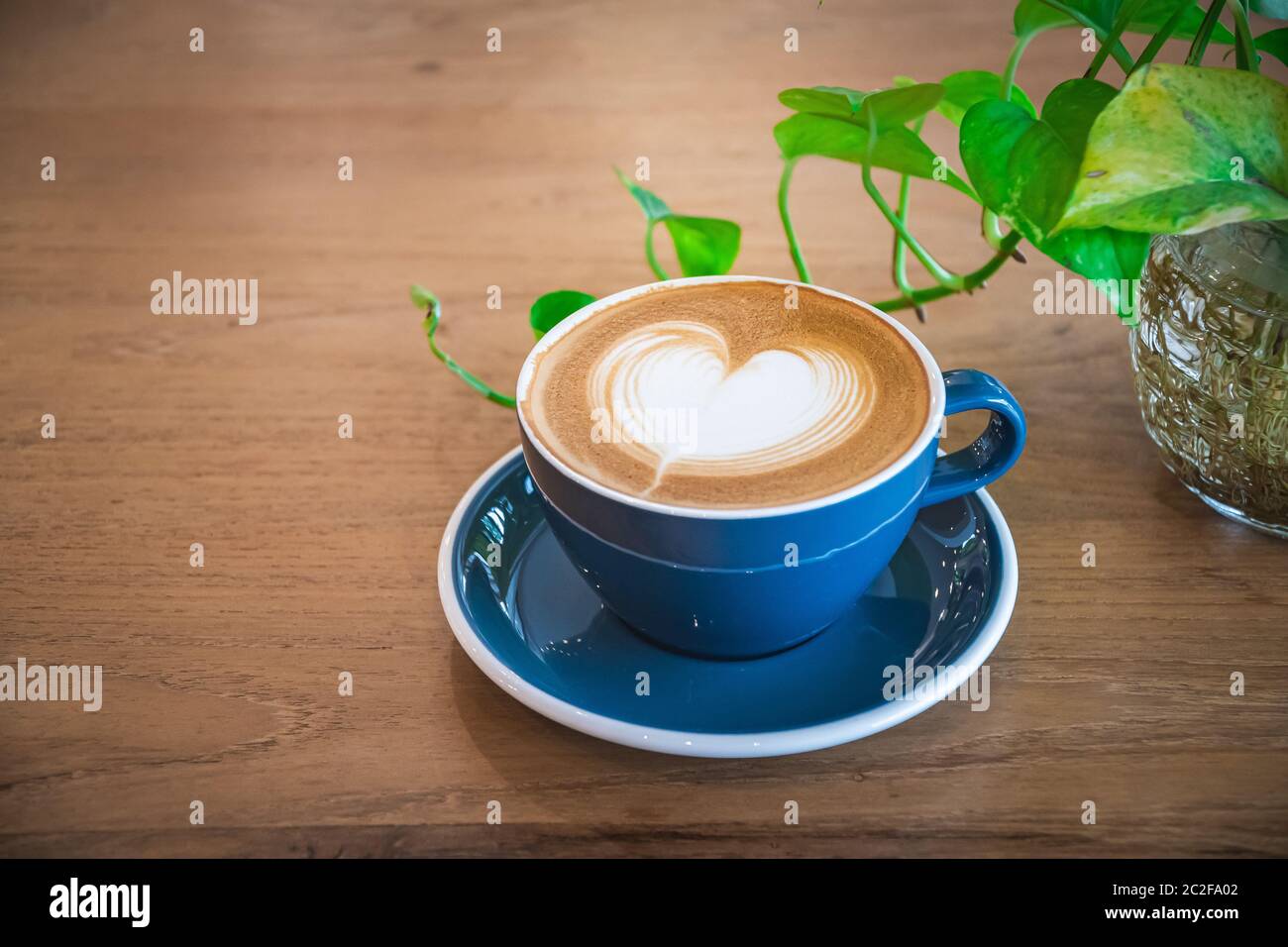 Bella una tazza blu di cappuccino caldo caffè con latte art su tavola di legno, fuoco selettivo per sfondo bevanda Foto Stock