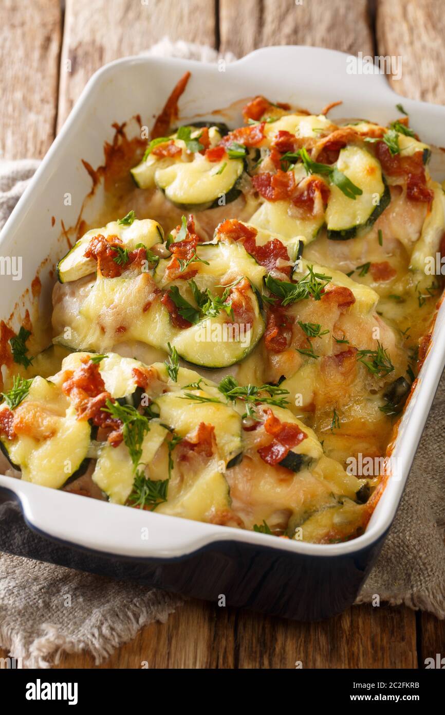 Casseruola di zucchine di pollo cremosa con pancetta primo piano in una teglia sul tavolo. Verticale Foto Stock