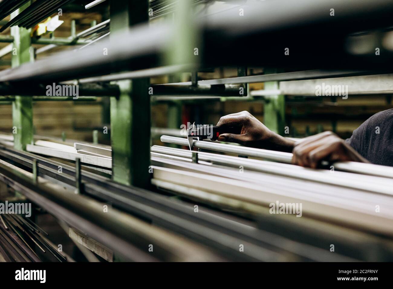 Materiale in acciaio su scaffali di stoccaggio che misura il lavoratore di fabbrica con l'attrezzo speciale. Primo piano e spazio per la copia. Rampe di alluminio Foto Stock