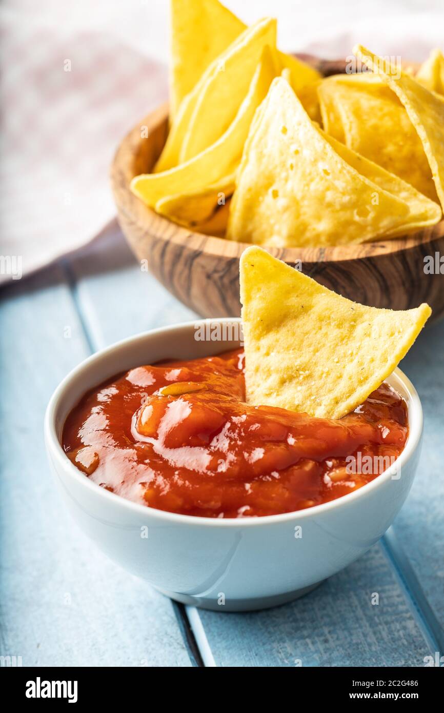 Il mais nacho chips e pomodoro dip. Giallo tortilla chips e salsa sul vecchio tavolo blu. Foto Stock