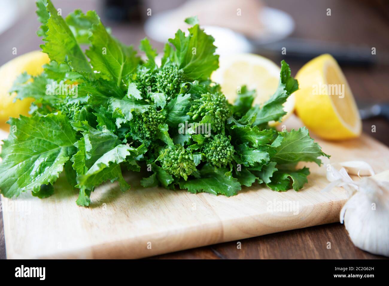 Broccoli rabe su un tagliere con i limoni in background Foto Stock