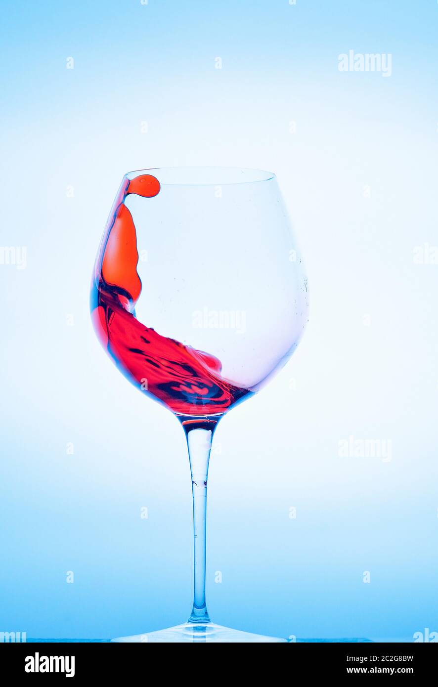spruzzare in un bicchiere di vino su sfondo blu Foto Stock