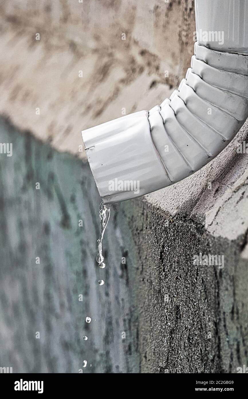 L'acqua che scorre fuori la fine di un eavestrough. Foto Stock