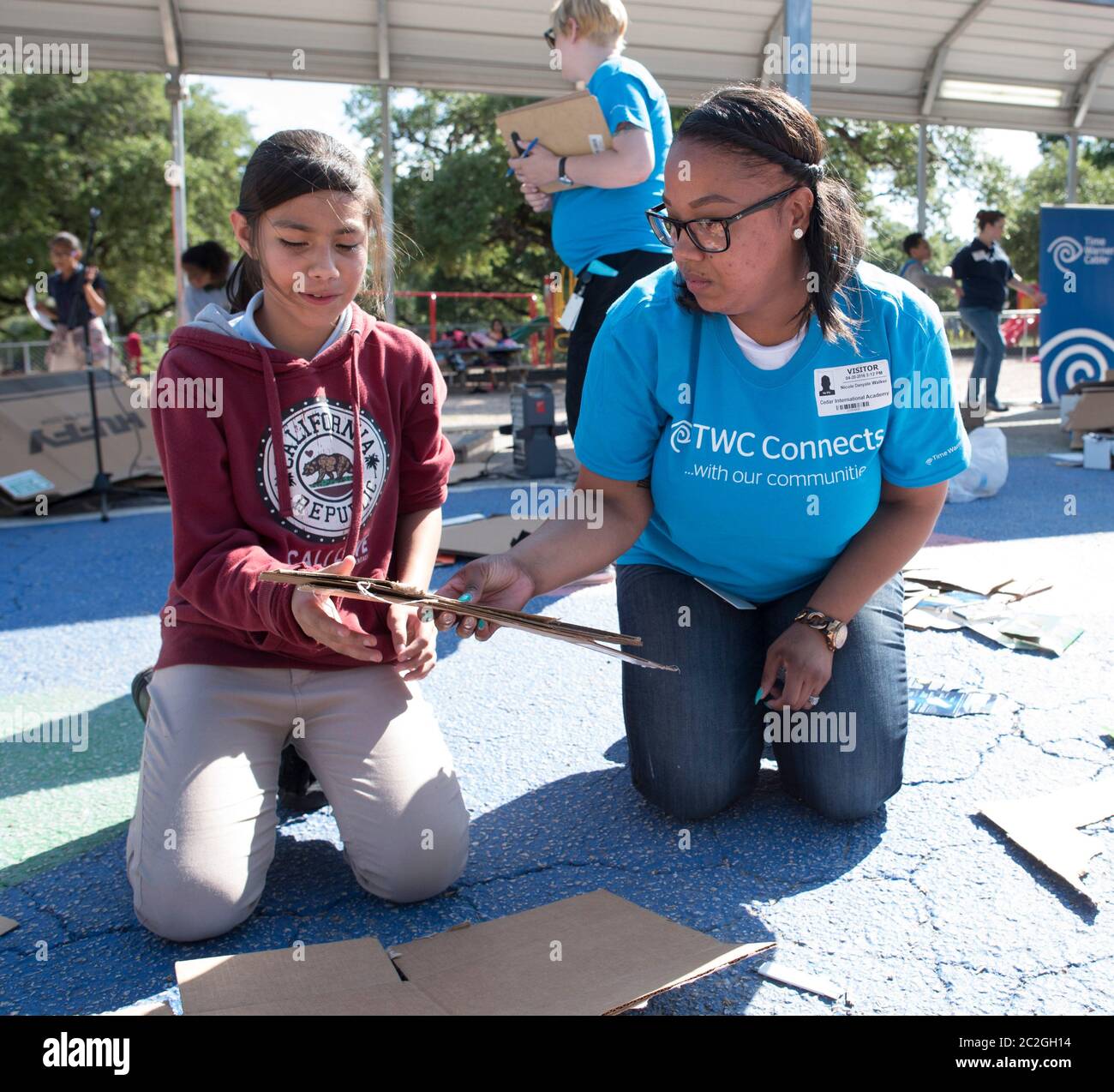 Austin Texas USA, aprile 20 2016: Un volontario adulto consiglia agli studenti della Cedars International Academy, che partecipano al programma Earth Day Cardboard Challenge della Cedars International Academy, mentre progettano e costruiscono una mostra scientifica in cartone e altri semplici prodotti riciclati. L'evento si è tenuto il giorno della Terra. ©Bob Daemmrich Foto Stock